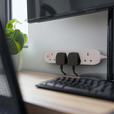 Desk setup with a computer monitor, keyboard, and power strip.
